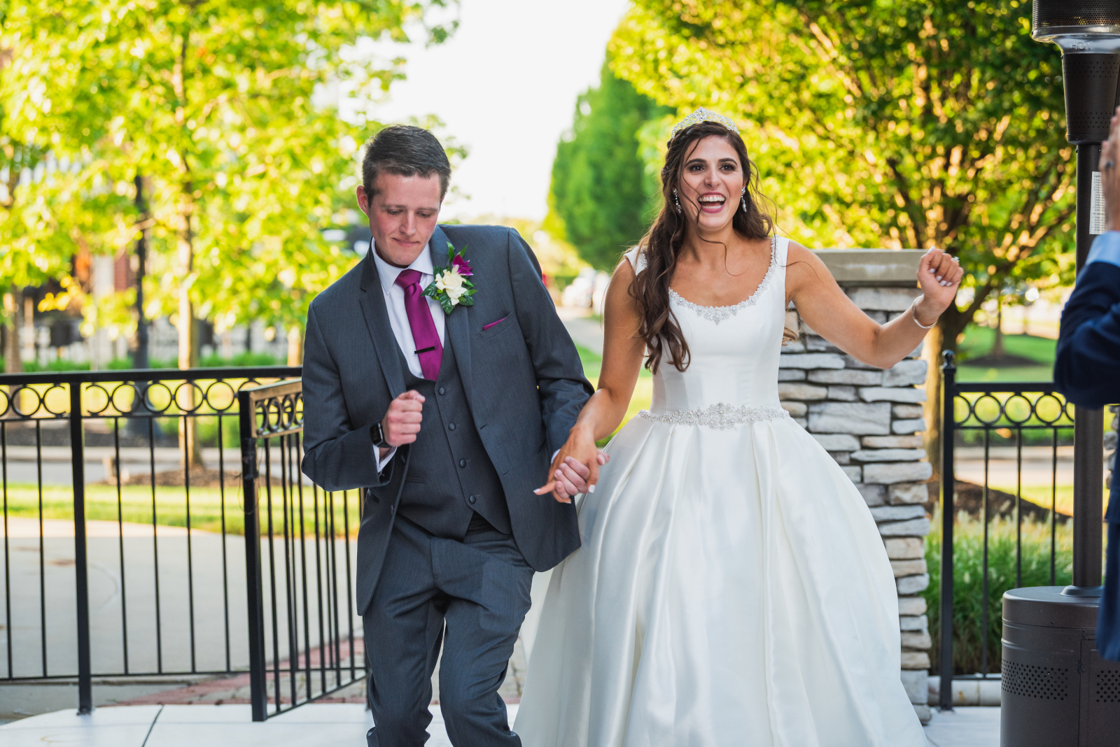 Bride and groom smiling, dancing, bridal party entrance, metal fence, green, trees, nature, sweet wedding reception at Crocker Park, Westlake OH