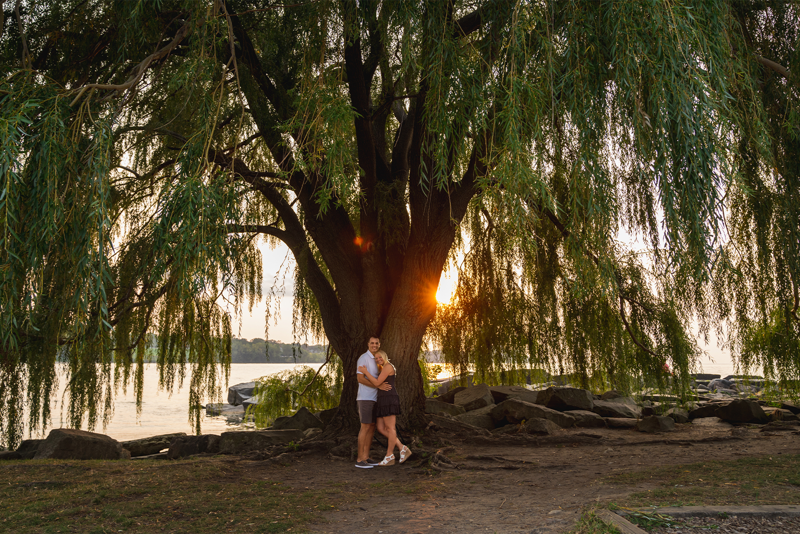 Man and woman fiancee engagement photo, couple portrait, weeping willow tree, sunset, sunset engagement photo, Lake Erie, cute, unique engagement portrait, Edgewater Beach, Cleveland Metroparks