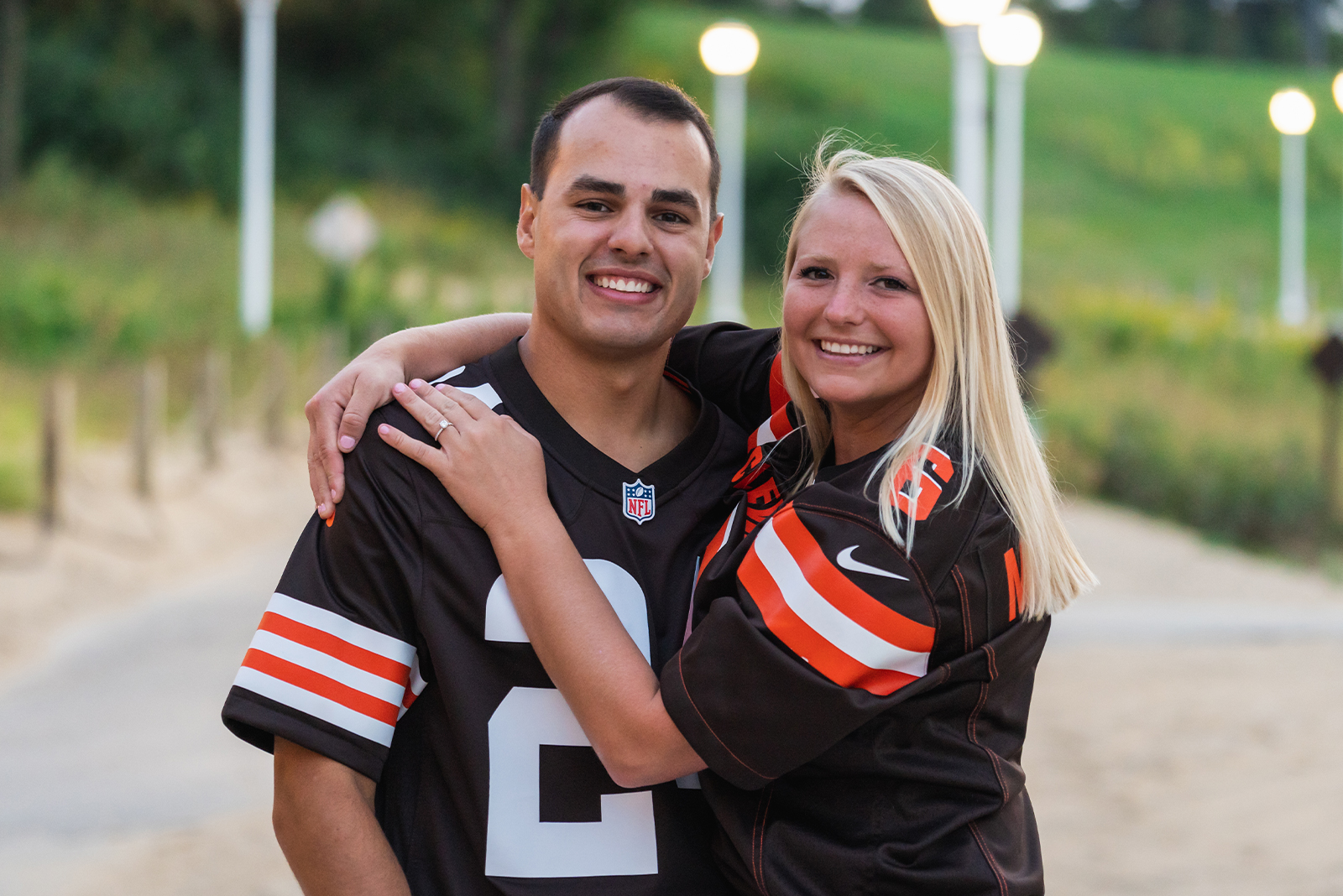 Man and woman fiancee engagement photo, couple portrait, sports jerseys, matching outfits, matching jerseys, Cleveland Browns, sports fans, green, nature, Lake Erie, Edgewater Beach, Cleveland Metroparks