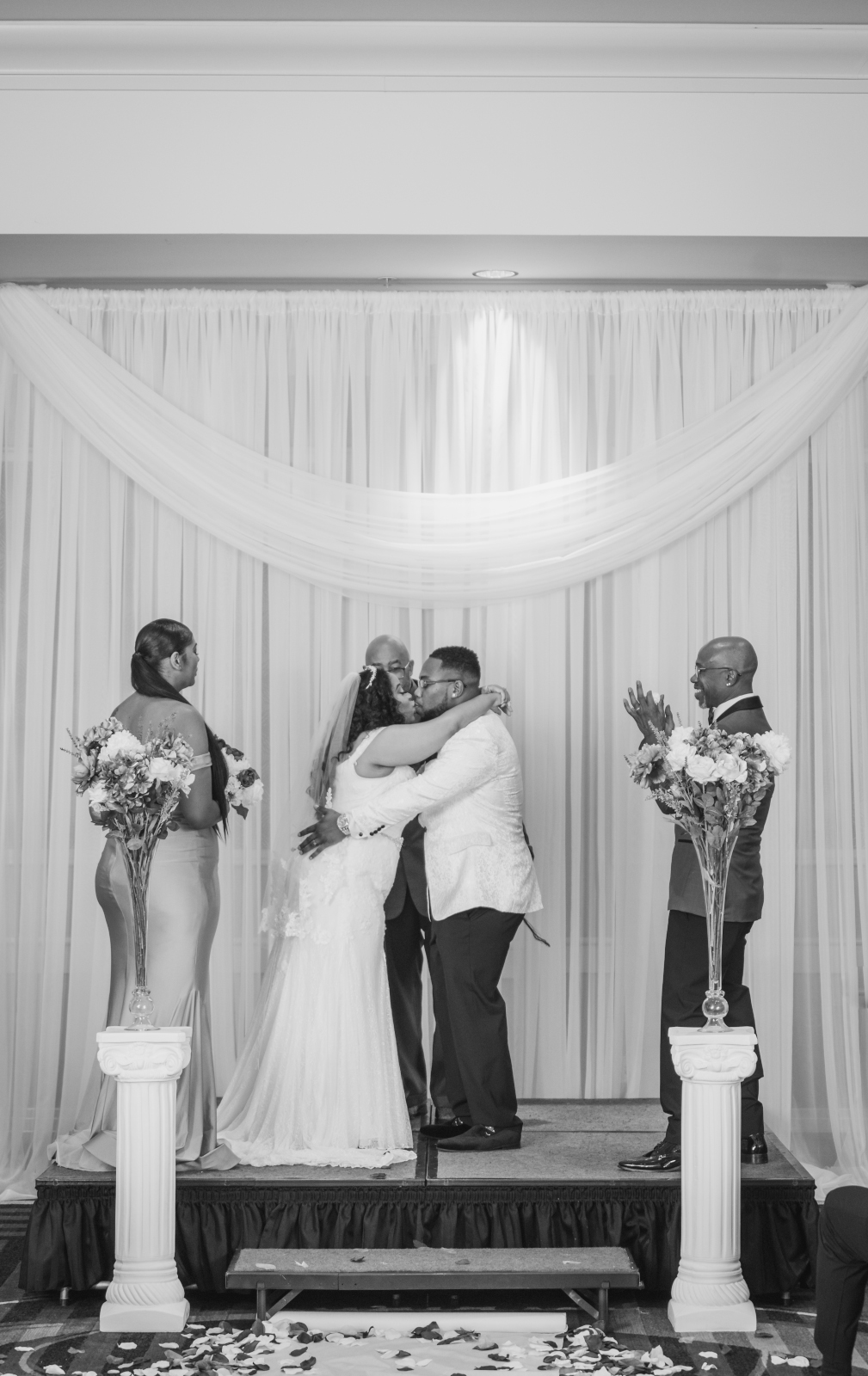 Bride and groom kiss, wedding ceremony, black and white wedding photo, father of the groom clapping, beautiful African American bride, African American wedding, romantic wedding ceremony at Hilton Akron/Fairlawn