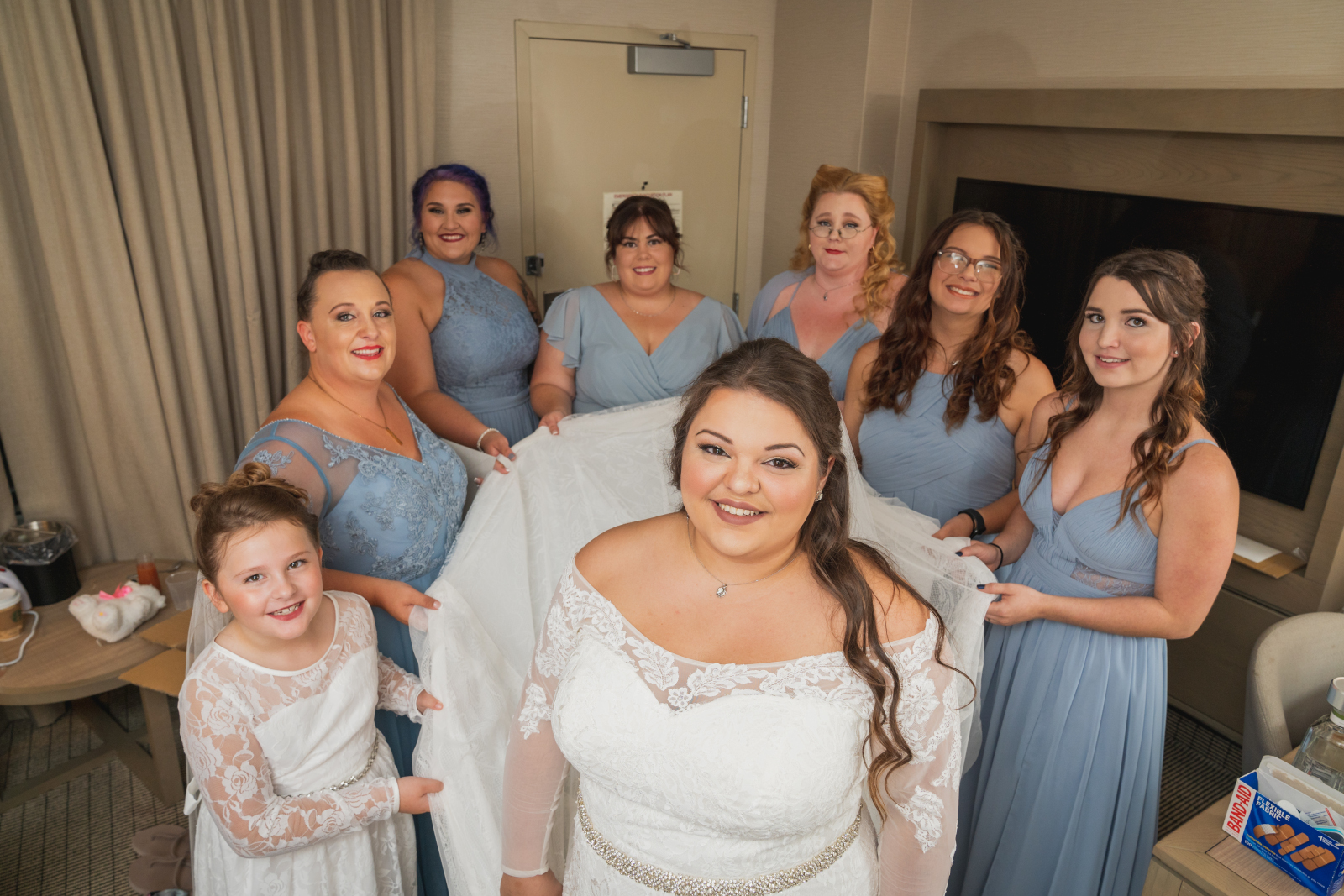 Bride with bridesmaids and flower girl holding up wedding dress train, getting ready, wedding preparation, bridal portrait, bridal party portrait, September wedding at Westfall Event Center