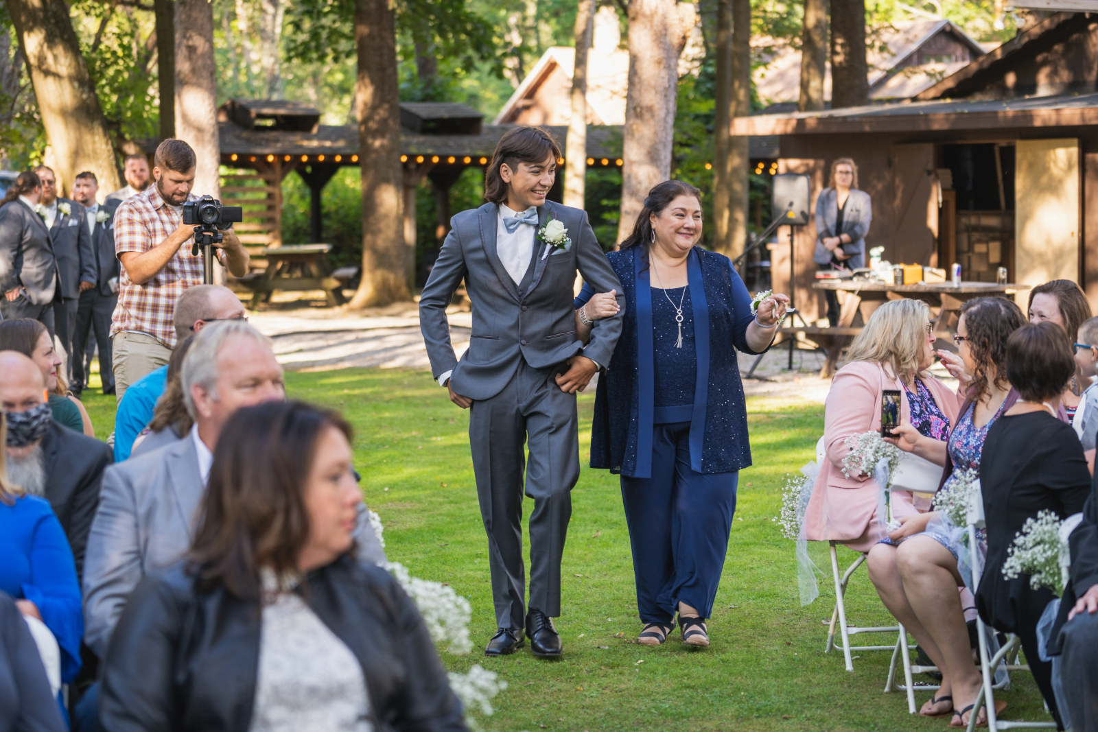 Groomsman and mother of the bride, bridal party processional, smile, green, trees, outdoor September wedding ceremony at Westfall Event Center