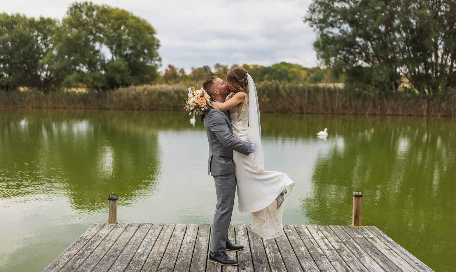 Bride and groom, kiss, wedding portrait, bridal portrait, nature, dock, pond, ducks, goose, fall wedding, rustic outdoor wedding ceremony at White Birch Barn